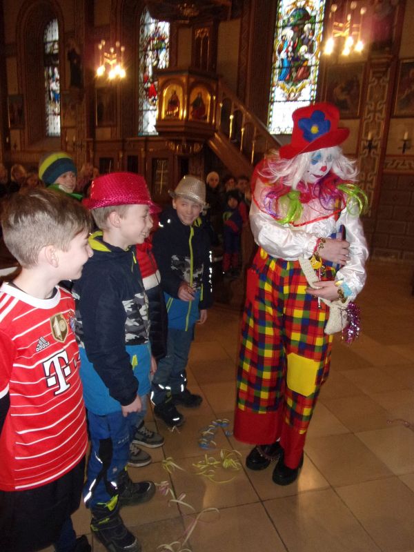 der Clown setzt den Kindern Hüte auf